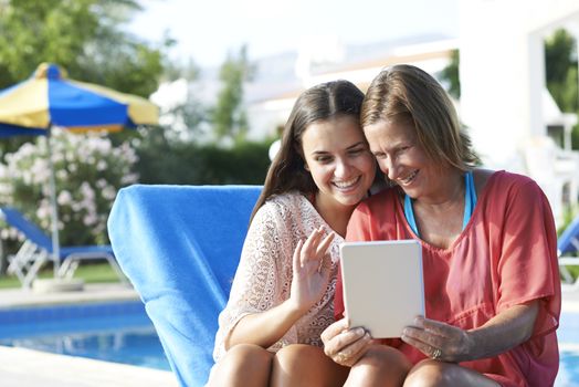 Mother and Daughter keeping in touch with friends and family using a digital tablet while on holiday