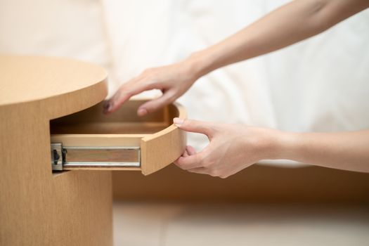 Woman hand opening a drawer in the wooden table.