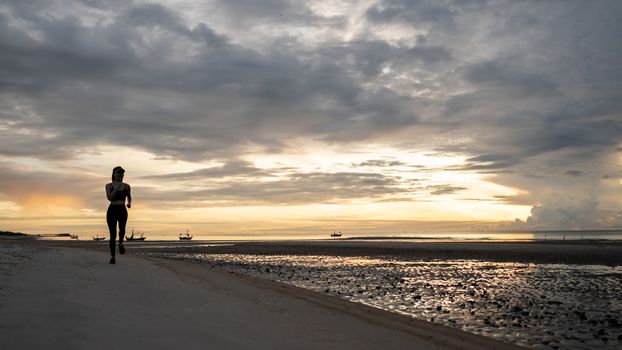 Woman jogging on beach in the morning.