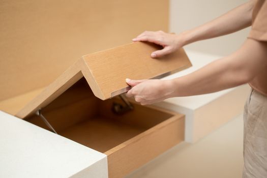 Woman hand opening cupboard of brown wooden table built in.