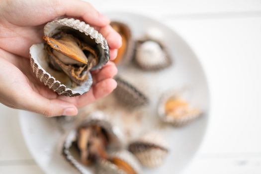 Big cockles seafood in woman hand, cockles or scallop fresh shellfish.