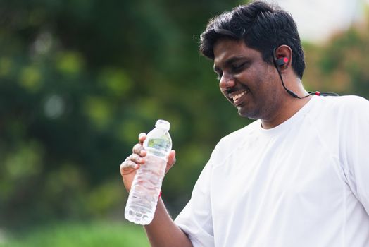 Close up Asian young sport runner black man wear athlete headphones he drinking water from a bottle after running at the outdoor street health park, healthy exercise workout concept