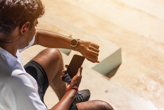 Close up Asian young athlete sport runner black man wear modern time smart watch and sync to a smartphone check running result after a training run at the outdoor, healthy exercise workout technology