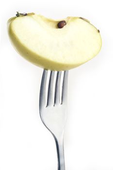 slice of apple pierced on a fork against plain background