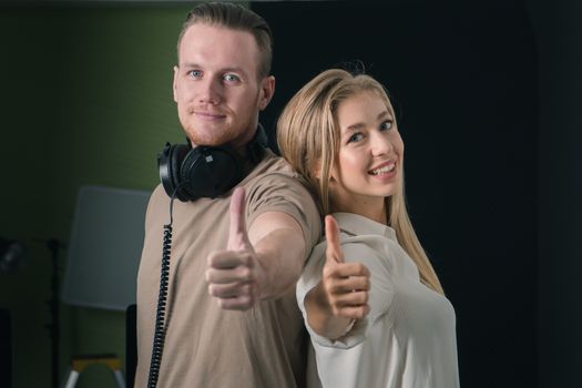 Young Caucasian women and men confident smiling.  talented and attractive female singer rehearsing in recording studio with producer or male musicians. Sound engineer check equipment for control audio