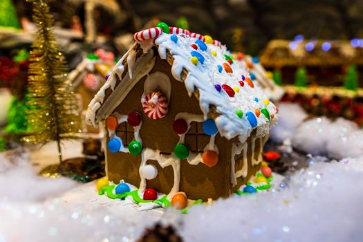 Colorful gingerbread house isolated on blurred background with Christmas decoration.