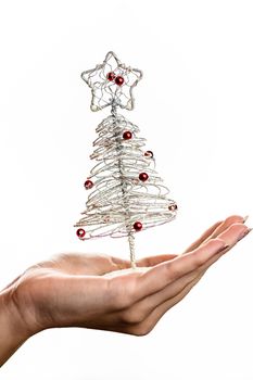 Hand holding small silver wire Christmas tree isolated on white background