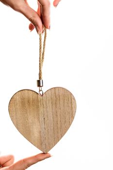 Hand holding heart shaped decoration isolated on white.