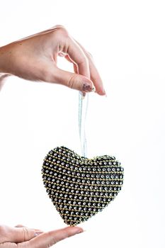 Hand holding heart shaped decoration isolated on white.