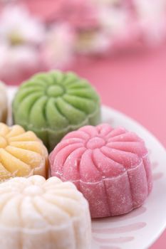 Colorful snow skin moon cake, sweet snowy mooncake, traditional savory dessert for Mid-Autumn Festival on pastel pale pink background, close up, lifestyle.