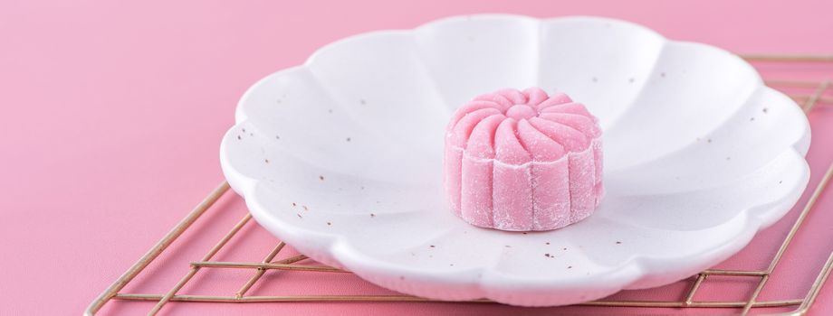 Colorful snow skin moon cake, sweet snowy mooncake, traditional savory dessert for Mid-Autumn Festival on pastel pale pink background, close up, lifestyle.