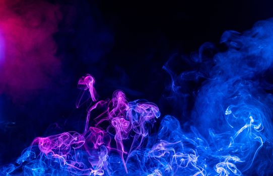 Conceptual image of multi-colored smoke isolated on dark black background, Halloween design element.