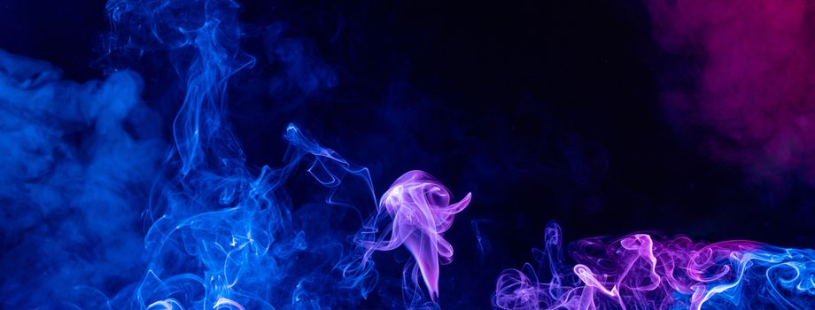 Conceptual image of multi-colored smoke isolated on dark black background, Halloween design element.