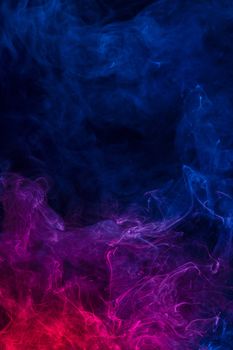 Conceptual image of multi-colored smoke isolated on dark black background, Halloween design element.