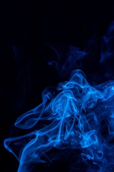 Conceptual image of blue color smoke isolated on dark black background, Halloween design element concept.