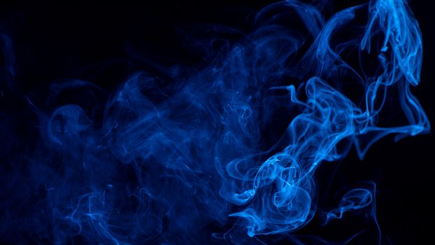 Conceptual image of blue color smoke isolated on dark black background, Halloween design element concept.