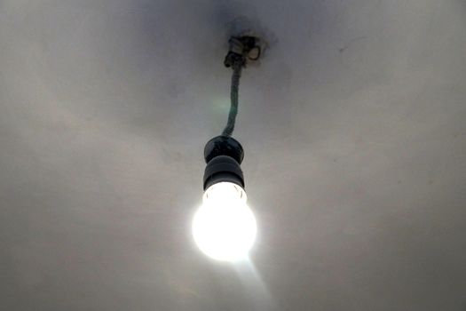 old included light bulb on the ceiling without lampshade.