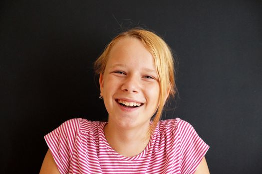 .portrait of a laughing teenage girl on a black background