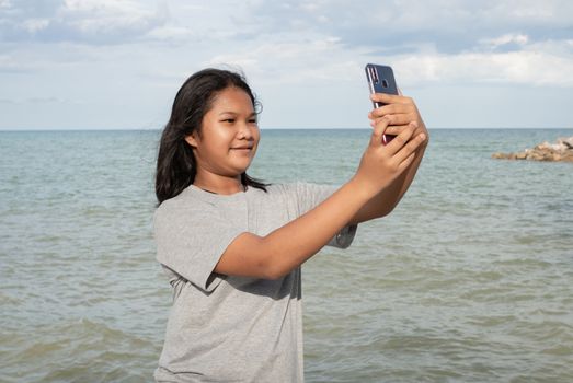 A girl using a phone to take a selfie on a sea background