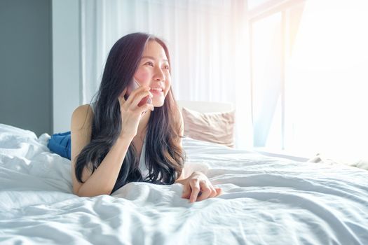 Young woman talking on the phone in bedroom at morning 