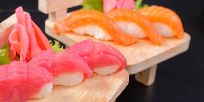 Japanese Cuisine - Sushi Roll on wood plate in black background