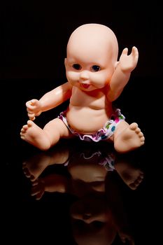 Little plastic doll baby on black background