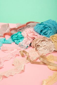 Abstract background with pile of color lace for Lingerie, panties, and bras on pink background. Delicate sophisticated glamorous elastic material. Using for Atelier and fabric store.