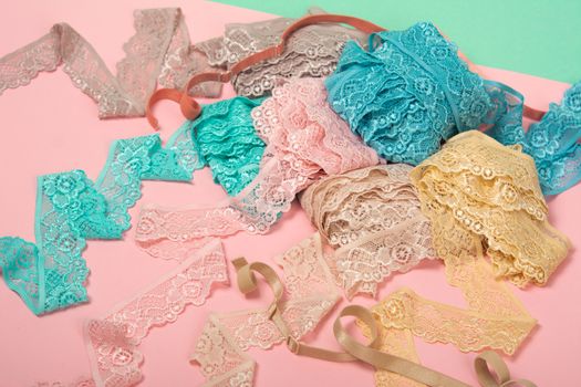 Abstract background with pile of color lace for Lingerie, panties, and bras on pink background. Delicate sophisticated glamorous elastic material. Using for Atelier and fabric store.