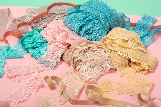 Abstract background with pile of color lace for Lingerie, panties, and bras on pink background. Delicate sophisticated glamorous elastic material. Using for Atelier and fabric store.