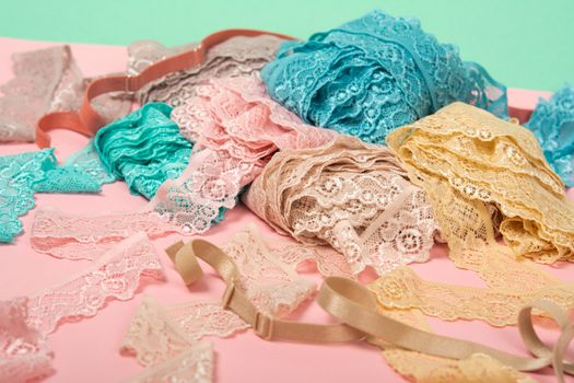 Abstract background with pile of color lace for Lingerie, panties, and bras on pink background. Delicate sophisticated glamorous elastic material. Using for Atelier and fabric store.