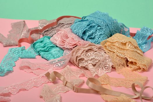 Abstract background with pile of color lace for Lingerie, panties, and bras on pink background. Delicate sophisticated glamorous elastic material. Using for Atelier and fabric store.