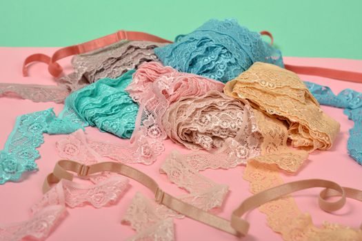 Abstract background with pile of color lace for Lingerie, panties, and bras on pink background. Delicate sophisticated glamorous elastic material. Using for Atelier and fabric store.