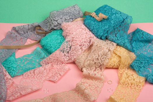 Abstract background with pile of color lace for Lingerie, panties, and bras on pink background. Delicate sophisticated glamorous elastic material. Using for Atelier and fabric store.