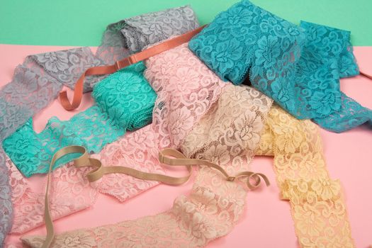 Abstract background with pile of color lace for Lingerie, panties, and bras on pink background. Delicate sophisticated glamorous elastic material. Using for Atelier and fabric store.