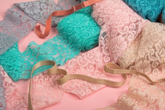 Abstract background with pile of color lace for Lingerie, panties, and bras on pink background. Delicate sophisticated glamorous elastic material. Using for Atelier and fabric store.