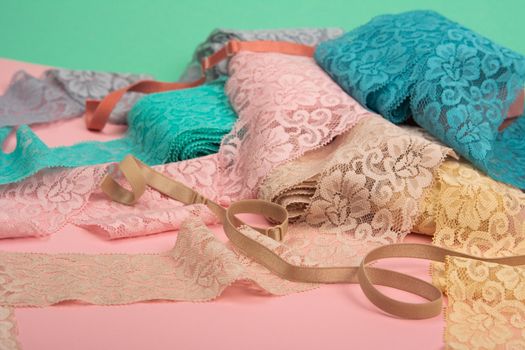 Abstract background with pile of color lace for Lingerie, panties, and bras on pink background. Delicate sophisticated glamorous elastic material. Using for Atelier and fabric store.