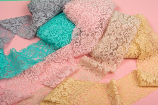 Abstract background with pile of color lace for Lingerie, panties, and bras on pink background. Delicate sophisticated glamorous elastic material. Using for Atelier and fabric store.
