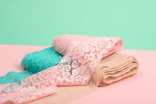 Abstract background with pile of color lace for Lingerie, panties, and bras on pink background. Delicate sophisticated glamorous elastic material. Using for Atelier and fabric store.
