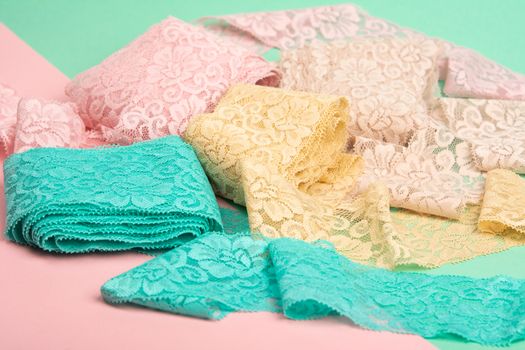 Abstract background with pile of color lace for Lingerie, panties, and bras on pink background. Delicate sophisticated glamorous elastic material. Using for Atelier and fabric store.