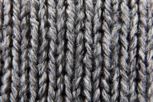 A grey ribbed knitted wool background texture macro with selective focus