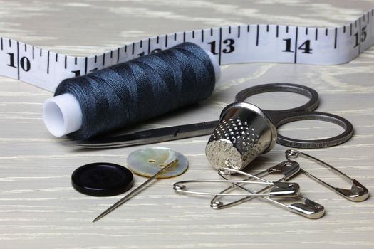 Supplies and equipment for sewing on wood work surface cotton tape measure scissors thimble needle pins buttons