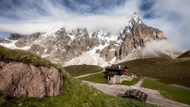 Cimon della Pala (also called "The Matterhorn of the Dolomites") with snow covered peaks on a sunny day with dramatic clouds above. San Martino di Castrozza, Italy.