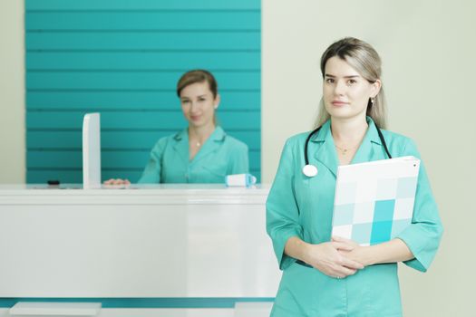 Two female doctors or nurses looking at the camera. Stethoscope phonendoscope on the neck. Holds a folder in his hands