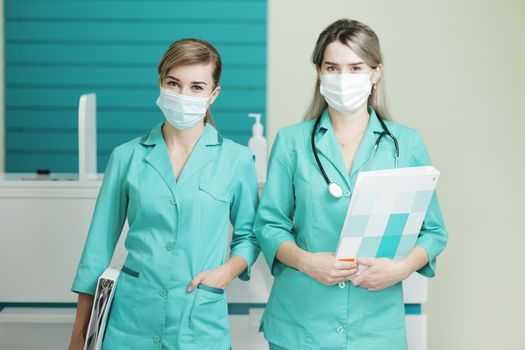 Two female doctor or nurse wearing medical masks looking at the camera. Stethoscope phonendoscope on the neck