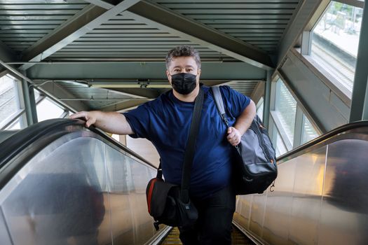 Man wear surgical face mask for protecting coronavirus, stand on the escalator, travel to the train, for trip during pandemic COVID-19