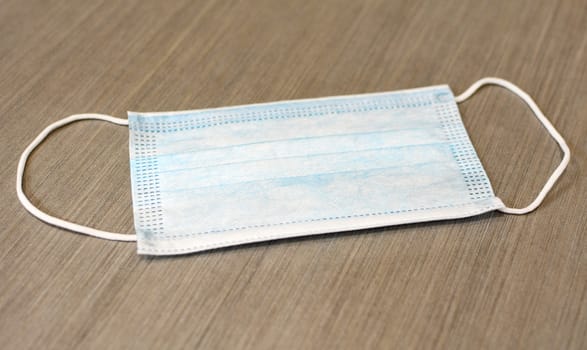 Blue surgical face mask protecting against Coronavirus Covid-19 placed on gray background.