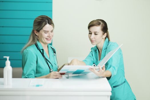 Two female doctor or nurse discussing patient treatment. Stethoscope phonendoscope on the neck. Holds a folder in his hands. Disinfectant on the table