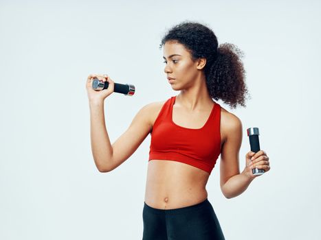 Sporty woman with dumbbells in hands doing exercises motivation workout in gym