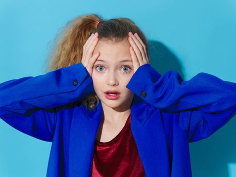 Surprised girl holding her head in blue coat fashion lifestyle Studio lifestyle