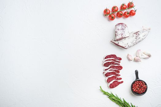 Sliced cuts of longaniza, dry cured spanish sausage with herbs and spices on white textured background, topview with space for text.